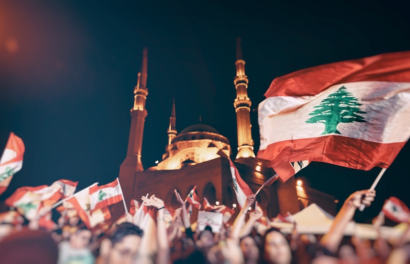 Revolution in Lebanon / ©Anna Om - stock.adobe.com, Anna Om Revolution in Lebanon, a crowd of people with Lebanese flags picket near the mosque and fight for their rights, power to people, togetherness, unity, and support of each other